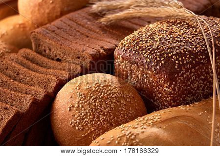 Assortement of Freshly baked traditional bread with ears of wheat. Sliceas of the bread and rulls. Background of bread. Delicious food. Fresh baking. Tasty and appetizing.