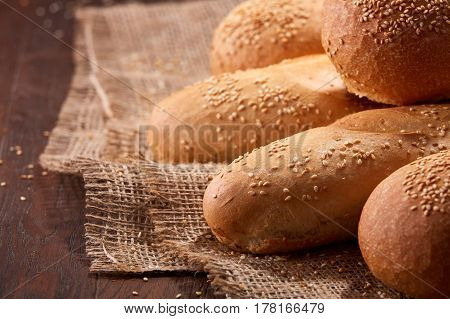 Freshly baked baguette bread and rulls on a burlap napkin on a wooden background. Close up. Delicious food. Fresh baking. Tasty and appetizing.