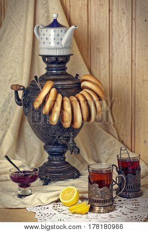 Russian samovar, tea with lemon in faceted glasses with cup holders and bublik. Tinted photo in vintage style.