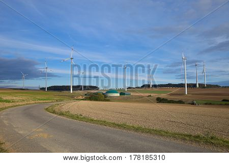 Different fermenters of a biogas plant with windmill in the background.Biogas plant with wind turbine.
