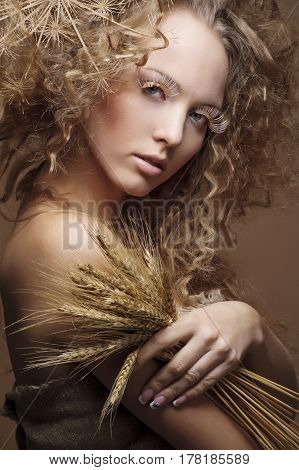 portrait of beautiful curly girl with wheat on a beige background