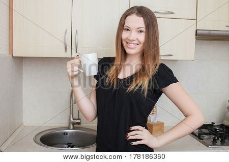 Beautiful young woman having morning coffee, relaxing hot drink, happy female holding cup of tea, pretty girl eating and drinking healthy food at home, health care and dieting concept.