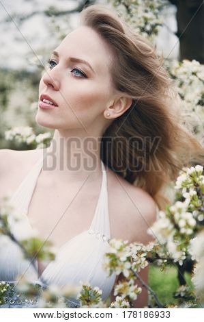 portrait of a beautiful blonde girl in a flowering garden