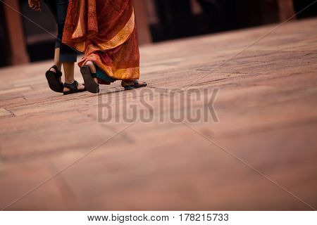 two ladies walking on a sanstone floor at fatehpur sikri