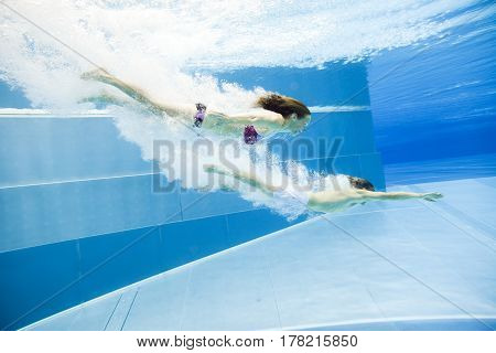 a young couple is jumping into the water from a diving plattform