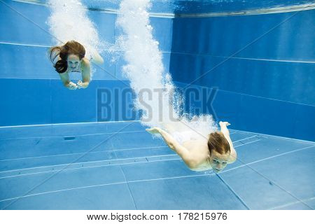 a young couple is jumping into the water from a diving plattform