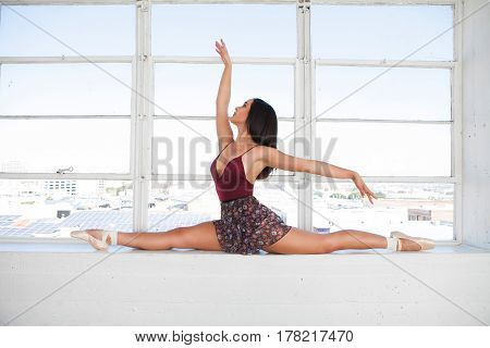 Beautiful talented woman doing the split at window background.