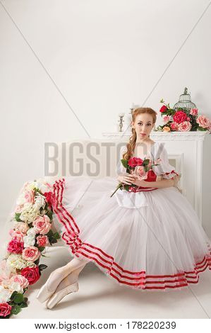 Cute ballerina in stage costume holding a bouquet of spring flowers. Retro dress.