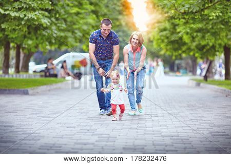 Young happy family of three having fun together outdoor. Pretty little daughter on her father back. Parents and girl look happy and smile. Happiness and harmony in family life. Family fun outside.