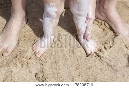 Mother applying sunblock cream to her baby on legs El Rompido Huelva Spain