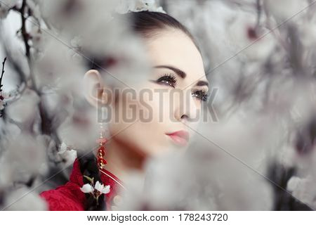 Attractive asian woman wearing kimono standing in blossoming garden.Close-up creative portrait outdoor on the nature. Girl looking away