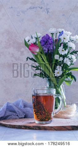 Cup Of Tea With Thyme And Bouquet Of Flowers On Background. Spring Concept