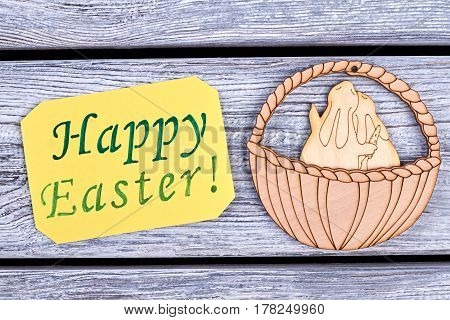 Happy Easter card. Plywood rabbits in a basket. Easter holiday congratulation.