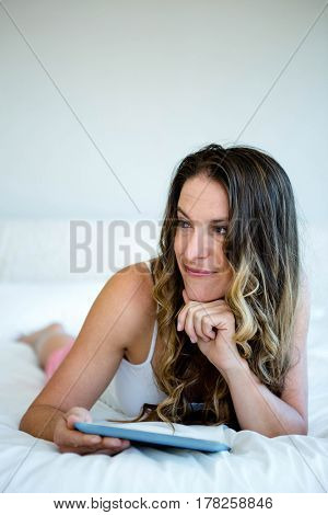 smiling woman lying on her stomach, reading on her tablet