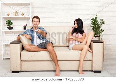 Dissapointed beautiful brunette woman in quarrel with her boyfriend. Indifferent man watching TV at home.