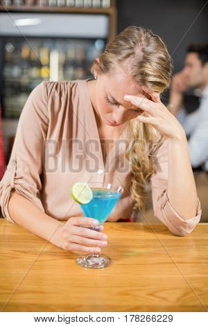 Tired woman with head in hand in a bar