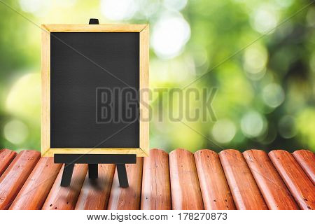 Blackboard on Log wood tabletop with blurred green nature background Mock up for display of product.