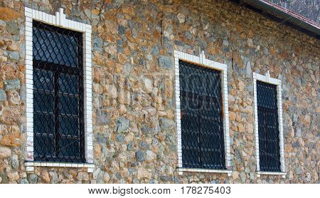 Closed window in a stone villa with a decorative grid on it