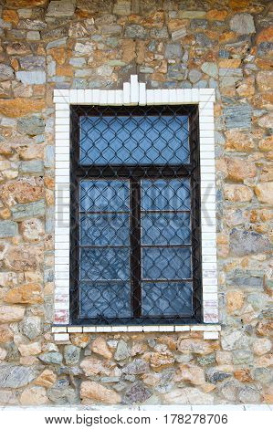 Closed window in a stone villa with a decorative grid on it