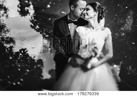 Sun Shines Newlyweds Faces While Thay Stand Behind A Lake