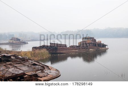 Old rusty sunken ships in water in a foggy day.