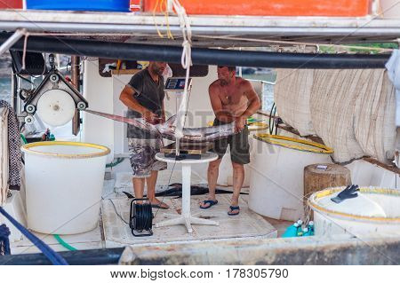 Bali Island Crete Greece - June 30 2016:Fishermen are weighing a big fish (sawfish) after successful fish catch on the fishing boat in the port located in village Bali on Crete island in Greece