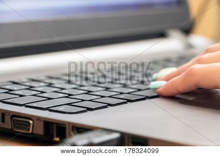 Part of the female hand on laptop keyboard. Selective focus