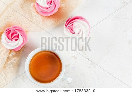 The concept of celebrating the mother's day. Spring relax. Cakes in the form of flowers (roses) with a cup of freshly brewed black tea on a white stone table. Copy space top view vertical