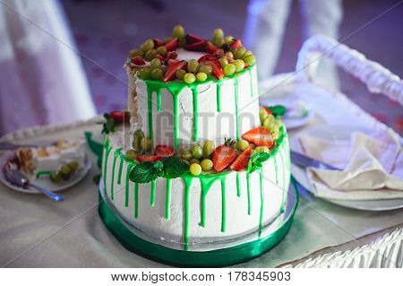 green style wedding cake with fruits on top.