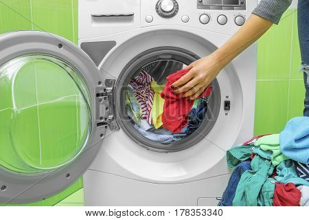 Preparing the wash cycle. Washing machine, hands and clothes.