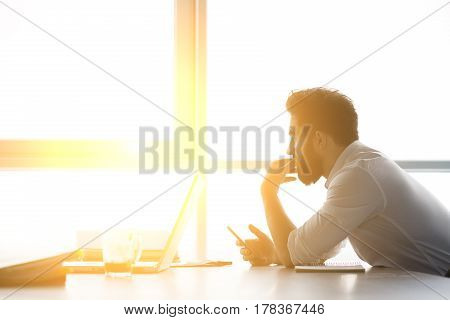 Toned of businessman waiting for interview while sitting at table and looking at window. Handsome man having stress before interview.