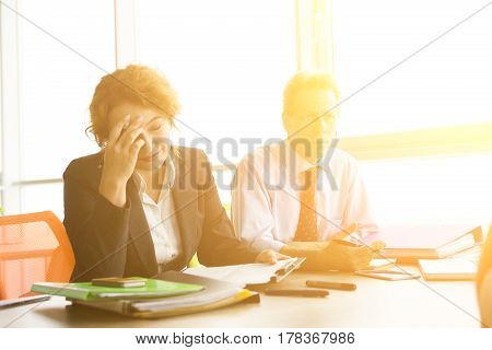 Toned of business lady looking tired after taking interview with new workers. Business people sitting at table in board room in office.