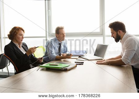 Business or freelance concept. Business people taking interview while sitting at table in office. Business representatives man and woman communicating with new worker.