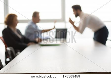 Closeup of bare table in board room in office. Handsome Indian man asking employees to give him place in their company.