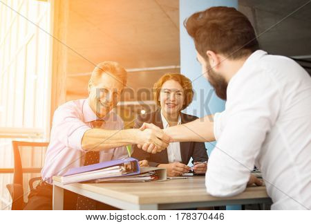 Toned of happy employees congratulating their future worker by shaking hands. Happy people ready to work all together to achieve their goal.