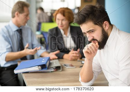 Young applicant having stress before interview while business employees communicating on background. Interview concept.