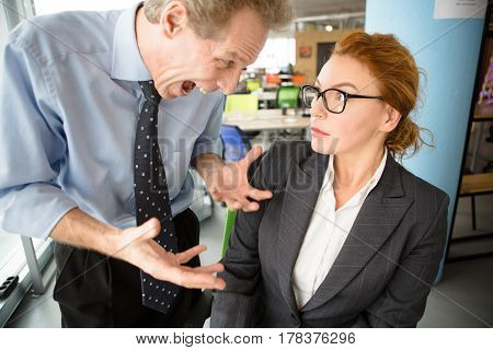 Closeup of lady in stress looking at her angry bosses screaming and shouting at her. Pretty lady in glasses will be fired. Mobbing, stress, work, scandal concepts.