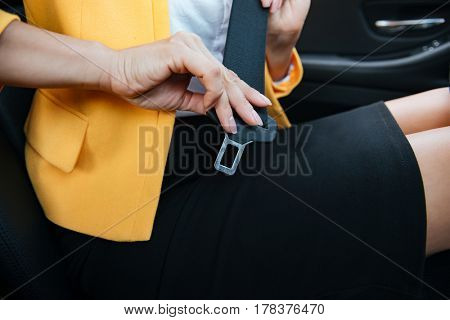Close up image of business woman sitting in a car putting on her seat belt