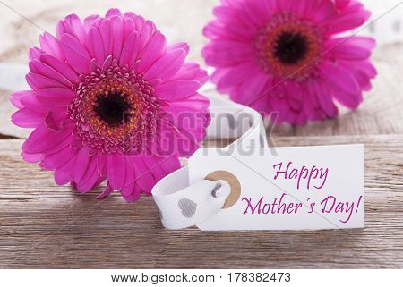 Label With English Text Happy Mothers Day. Pink Spring Gerbera Blossom. Vintage, Rutic Or Aged Wooden Background. Card For Spring Greetings.