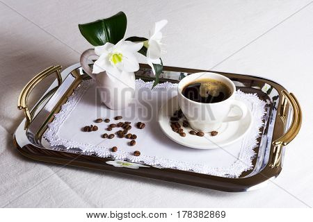 Cup of coffee on exquisite embroidered napkin on silver serving tray. Best hotel service concept.