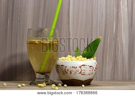 A glass of a summer drink Jal zeera or cumin lemonade with spices and chickpea flour balls on a wooden background selective focus.