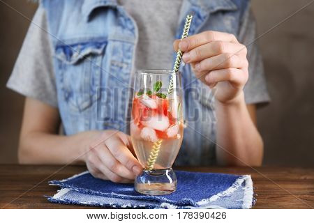 Woman with glass of delicious wine spritzer at table