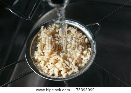 Washing brown rice with water in sieve
