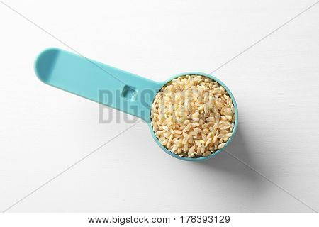 Measure scoop full of brown rice on white background