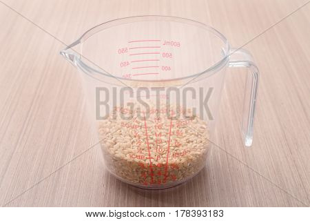 Brown rice in measure glass on wooden kitchen table