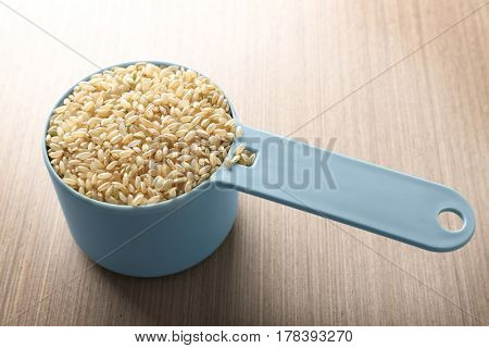 Measure scoop with brown rice on wooden kitchen table