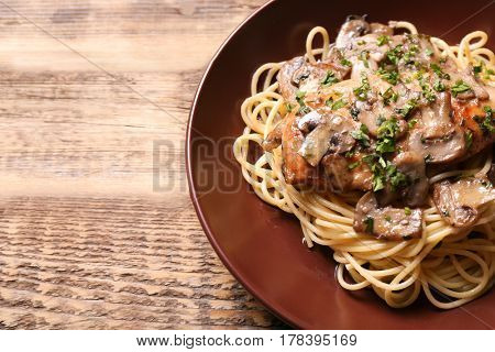 Plate with delicious chicken marsala and spaghetti on table