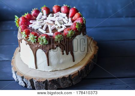 Delicious cake with fresh strawberry and dark chocolate sauce and plate with marshmallows