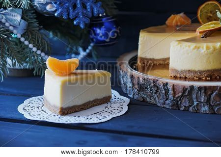 Christmas cake with cinnamon and it's slace, orange decoration under Christmas tree