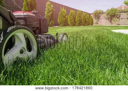 Lawn mower in the garden on green grass